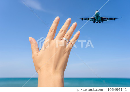 Female hand with a ring with a drawn plane holding a plane flying in the sky. Traveling on an airplane concept. Text space. Impressive paradise. Hot beach Mai Khao. Amazing landscape Female hand with a ring with a drawn plane holding a plane flying in the sky. Traveling on an airplane concept. Text space. Impressive paradise. Hot beach Mai Khao. Amazing landscape 106494141