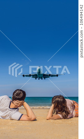 Man and woman tourists have fun on the beach watching the landing planes. Traveling on an airplane concept. Text space. Island Phuket in Thailand. Impressive paradise. Hot beach Mai Khao. Amazing Man and woman tourists have fun on the beach watching the landing planes. Traveling on an airplane concept. Text space. Island Phuket in Thailand. Impressive paradise. Hot beach Mai Khao. Amazing 106494142