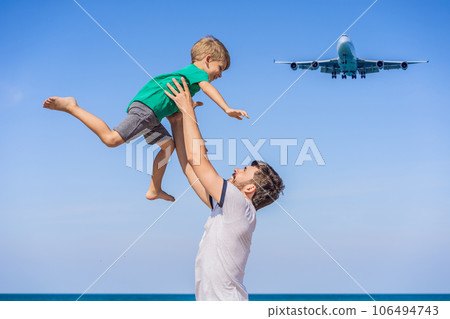 Dad and son have fun on the beach watching the landing planes. Traveling on an airplane with kids concept. Text space. Island Phuket in Thailand. Impressive paradise. Hot beach Mai Khao. Amazing 106494743
