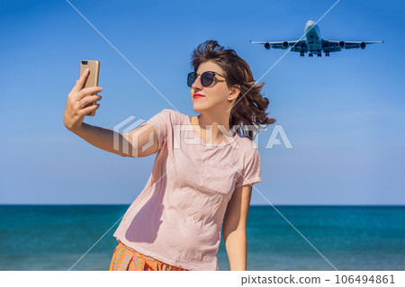 Woman makes a selfie on the beach watching the landing planes. Traveling on an airplane concept. Text space. Island Phuket in Thailand. Impressive paradise. Hot beach Mai Khao. Amazing landscape Woman makes a selfie on the beach watching the landing planes. Traveling on an airplane concept. Text space. Island Phuket in Thailand. Impressive paradise. Hot beach Mai Khao. Amazing landscape 106494861