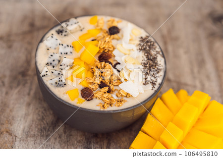 Smoothie bowls made with mango, banana, granola, grated coconut, dragon fruit, chia seeds and mint on wooden background. Concept fruits, vitamins 106495810