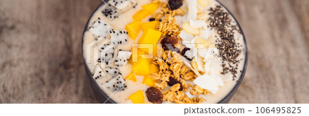Smoothie bowls made with mango, banana, granola, grated coconut, dragon fruit, chia seeds and mint on wooden background. Concept fruits, vitamins BANNER, LONG FORMAT 106495825