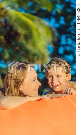 Summer lifestyle portrait of mother and son sitting on the orange inflatable sofa on the beach of tropical island. Relaxing and enjoying life on air bed VERTICAL FORMAT for Instagram mobile story or Summer lifestyle portrait of mother and son sitting on the orange inflatable sofa on the beach of tropical island. Relaxing and enjoying life on air bed VERTICAL FORMAT for Instagram mobile story or 106496866
