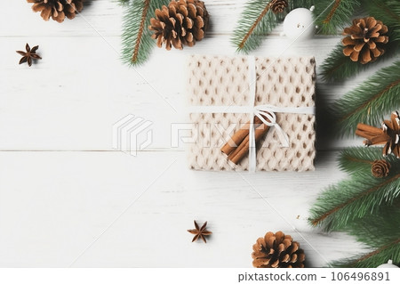 Christmas composition. Christmas gift, knitted blanket, pine cones, fir branches on wooden white background. Flat lay, top view, copy space 106496891