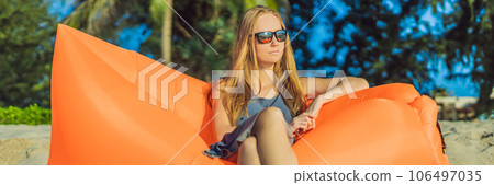 Summer lifestyle portrait of pretty girl sitting on the orange inflatable sofa on the beach of tropical island. Relaxing and enjoying life on air bed BANNER, LONG FORMAT Summer lifestyle portrait of pretty girl sitting on the orange inflatable sofa on the beach of tropical island. Relaxing and enjoying life on air bed BANNER, LONG FORMAT 106497035