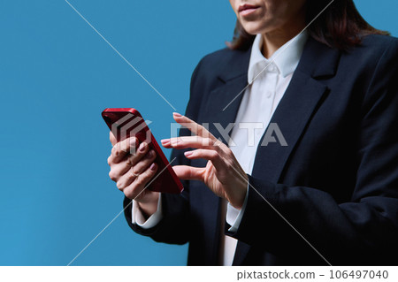 Closeup of business woman's hands using smartphone, on blue background 106497040