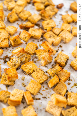 Cooling freshly dried croutons on a baking sheet lined with parchment paper. Cooling freshly dried croutons on a baking sheet lined with parchment paper. 106498042
