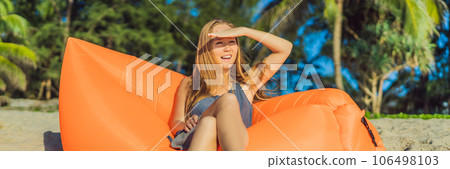 Summer lifestyle portrait of pretty girl sitting on the orange inflatable sofa on the beach of tropical island. Relaxing and enjoying life on air bed BANNER, LONG FORMAT Summer lifestyle portrait of pretty girl sitting on the orange inflatable sofa on the beach of tropical island. Relaxing and enjoying life on air bed BANNER, LONG FORMAT 106498103