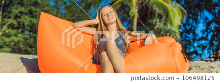 Summer lifestyle portrait of pretty girl sitting on the orange inflatable sofa on the beach of tropical island. Relaxing and enjoying life on air bed BANNER, LONG FORMAT Summer lifestyle portrait of pretty girl sitting on the orange inflatable sofa on the beach of tropical island. Relaxing and enjoying life on air bed BANNER, LONG FORMAT 106498125