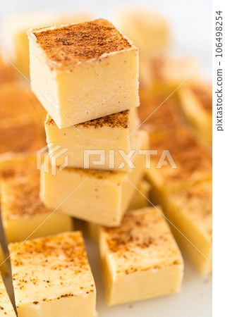Homemade eggnog fudge pieces on a white cutting board. Homemade eggnog fudge pieces on a white cutting board. 106498254