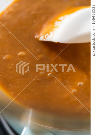 Melting chocolate chips and other ingredients in a glass mixing bowl over boiling water to prepare caramel fudge. Melting chocolate chips and other ingredients in a glass mixing bowl over boiling water to prepare caramel fudge. 106498532