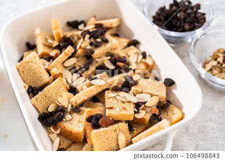 Baking bread pudding with raising and almond slivers in a white casserole dish. 106498843
