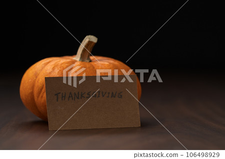 Small orange classic pumpkin on wood table with thanksgiving paper card Small orange classic pumpkin on wood table with thanksgiving paper card 106498929