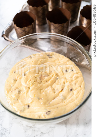 Scooping bread dough into paper liners to bake mini Easter bread kulich. Scooping bread dough into paper liners to bake mini Easter bread kulich. 106499569