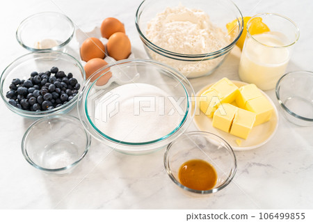 Measured ingredients in glass mixing bowls to bake lemon blueberry bundt cake. 106499855