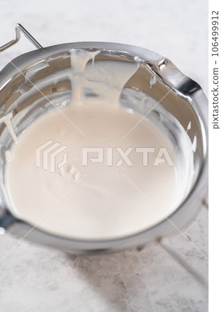 Melted white chocolate chips in a stainless steel double boiler pot. Melted white chocolate chips in a stainless steel double boiler pot. 106499912