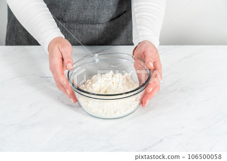 Mixing ingredients in a glass mixing bowl to bake mascarpone tart with fresh berries. 106500058