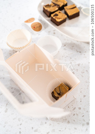 Packaging homemade chocolate fudge with peanut butter swirl into a white gift box. Packaging homemade chocolate fudge with peanut butter swirl into a white gift box. 106500135