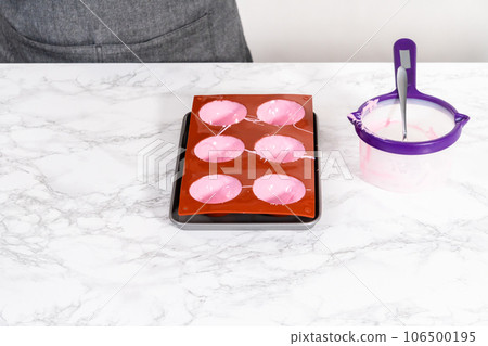 Filling in silicone chocolate molds with melted pink chocolate to prepare hot chocolate bombs. Filling in silicone chocolate molds with melted pink chocolate to prepare hot chocolate bombs. 106500195