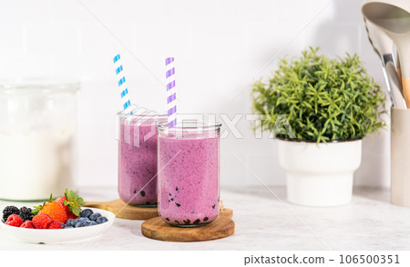 Pouring freshly made mixed berry boba smoothie into a drinking glass. Pouring freshly made mixed berry boba smoothie into a drinking glass. 106500351