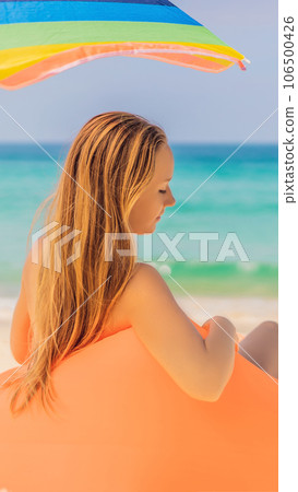 Summer lifestyle portrait of pretty girl sitting on the orange inflatable sofa on the beach of tropical island. Relaxing and enjoying life on air bed VERTICAL FORMAT for Instagram mobile story or Summer lifestyle portrait of pretty girl sitting on the orange inflatable sofa on the beach of tropical island. Relaxing and enjoying life on air bed VERTICAL FORMAT for Instagram mobile story or 106500426