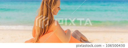 Summer lifestyle portrait of pretty girl sitting on the orange inflatable sofa on the beach of tropical island. Relaxing and enjoying life on air bed BANNER, LONG FORMAT 106500430