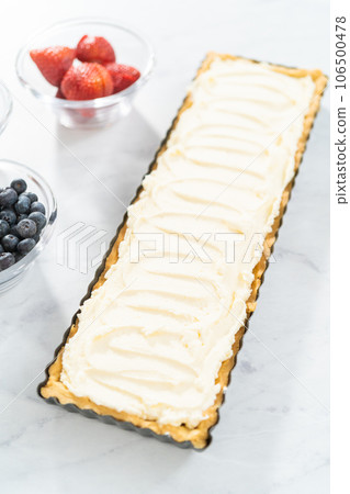 Filling mascarpone tart with cheese filling and decorating with fresh berries. 106500478