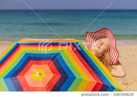 Young woman on the beach in a hat and beach umbrella Young woman on the beach in a hat and beach umbrella 106500626