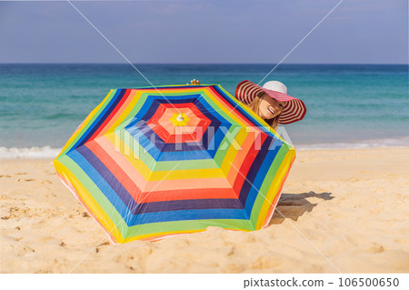 Young woman on the beach in a hat and beach umbrella Young woman on the beach in a hat and beach umbrella 106500650