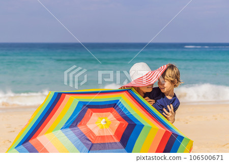 Mother and son on the beach in a hat and beach umbrella 106500671
