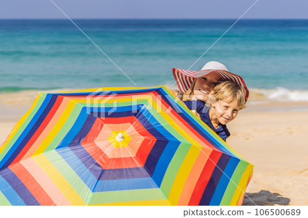 Mother and son on the beach in a hat and beach umbrella Mother and son on the beach in a hat and beach umbrella 106500689