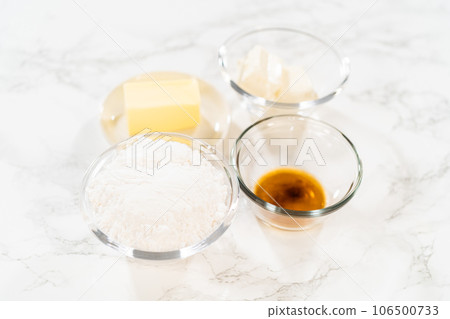 Measured ingredients in glass mixing bowls to bake no-yeast cinnamon roll cupcakes. 106500733