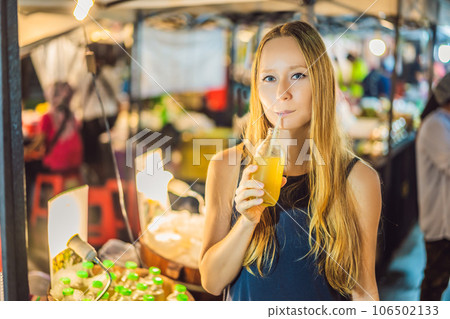 Woman drinking sugar cane juice on the Asian market 106502133