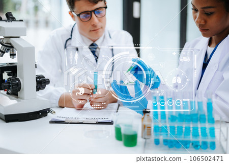 Focused mature male doctor and African female nurse look at tablet and laptop screen discuss anamnesis together. Concentrated diverse medical professionals 106502471