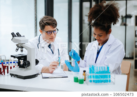 Focused mature male doctor and African female nurse look at tablet and laptop screen discuss anamnesis together. Concentrated diverse medical professionals 106502473