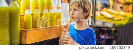 Boy drinking sugar cane juice on the Asian market BANNER, LONG FORMAT 106502849