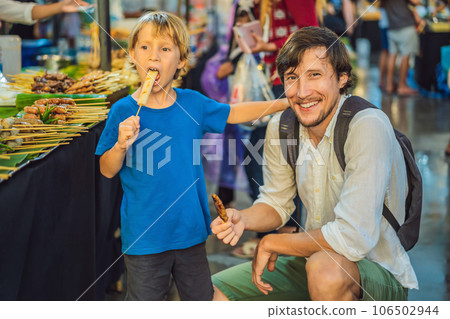 Dad and son are tourists on Walking street Asian food market 106502944