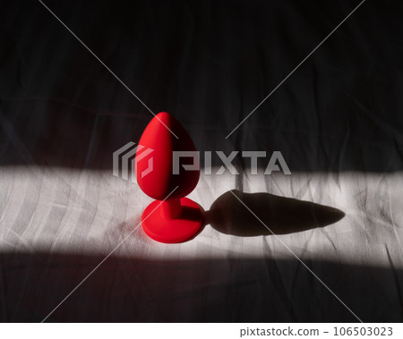 Red silicone anal plug on a white sheet.  106503023