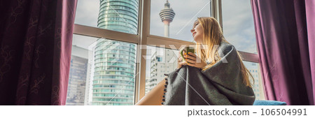 Woman wrapped in a blanket and looking at the big city BANNER, LONG FORMAT 106504991