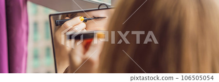 Young woman does makeup sitting by the window with a panoramic view of the skyscrapers and the big city BANNER, LONG FORMAT Young woman does makeup sitting by the window with a panoramic view of the skyscrapers and the big city BANNER, LONG FORMAT 106505054