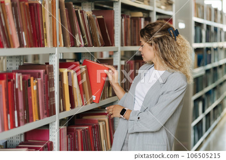 Attractive blond woman taking books from shelf in university library. Side view 106505215