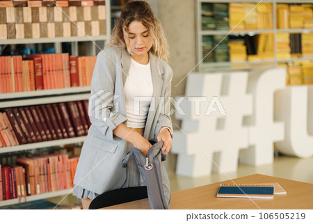 Female student finish study in public library and puts the laptop in the bag Female student finish study in public library and puts the laptop in the bag 106505219