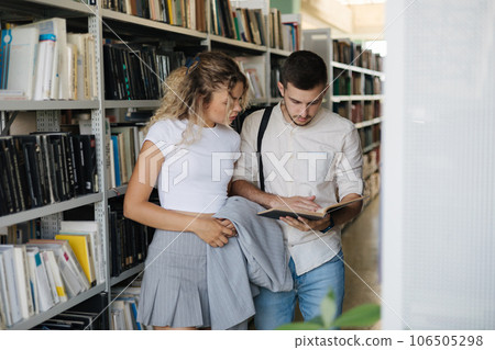 Handsome man and attractive female looking for book in university library. Woman show something to classmate in book Handsome man and attractive female looking for book in university library. Woman show something to classmate in book 106505298