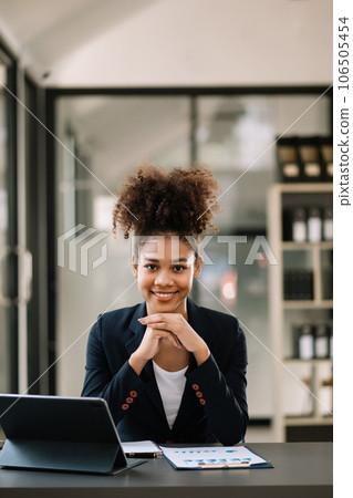 Young attractive Africa female office worker business suits smiling at camera in office . Young attractive Africa female office worker business suits smiling at camera in office . 106505454