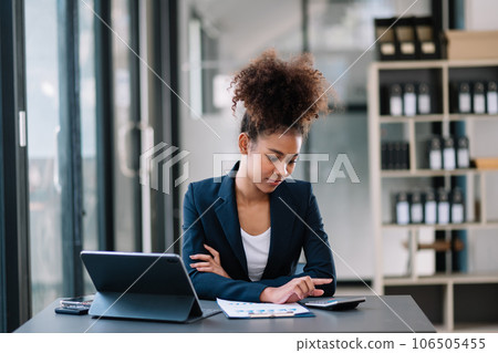 Young beautiful woman typing on tablet and laptop while sitting at the working table office Young beautiful woman typing on tablet and laptop while sitting at the working table office 106505455