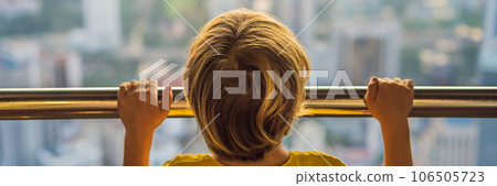Little boy looks at Kuala lumpur cityscape. Panoramic view of Kuala Lumpur city skyline evening at sunset skyscrapers building in Malaysia. Traveling with kids concept BANNER, LONG FORMAT 106505723