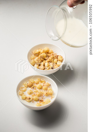 Breakfast with granola and milk in small bowls with a glass decanter on a white background 106505992