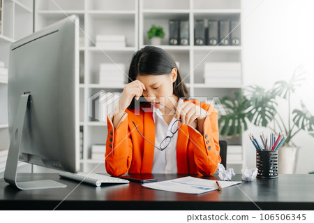 Asian woman feeling migraine head strain.Overworked businesswoman financier while working on laptop and tablet at office. Asian woman feeling migraine head strain.Overworked businesswoman financier while working on laptop and tablet at office. 106506345