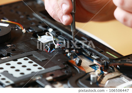 Repaiman with screwdriver fixing disassembled laptop parts. Technical support and fixing gadgets problems. Servicing, repairing, cleaning, maintaining computers. Repair shop. Hardware maintenanc Repaiman with screwdriver fixing disassembled laptop parts. Technical support and fixing gadgets problems. Servicing, repairing, cleaning, maintaining computers. Repair shop. Hardware maintenanc 106506447