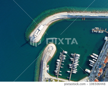 Aerial view of luxury sailing yachts and boats in yacht club near wooden piers. Top view of european city. Large boat parking near sea coast. Road to the lighthouse. Yachting in summer concept. 106506448